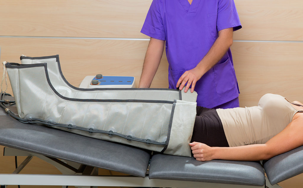 Doctor checking legs pressotherapy machine on woman
